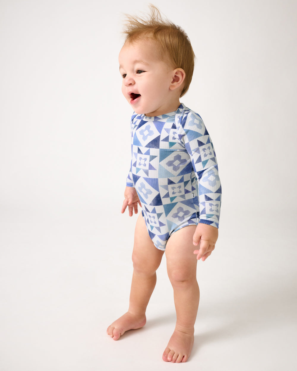 Standing baby wearing the Patchwork Indigo Ribbed Bodysuit