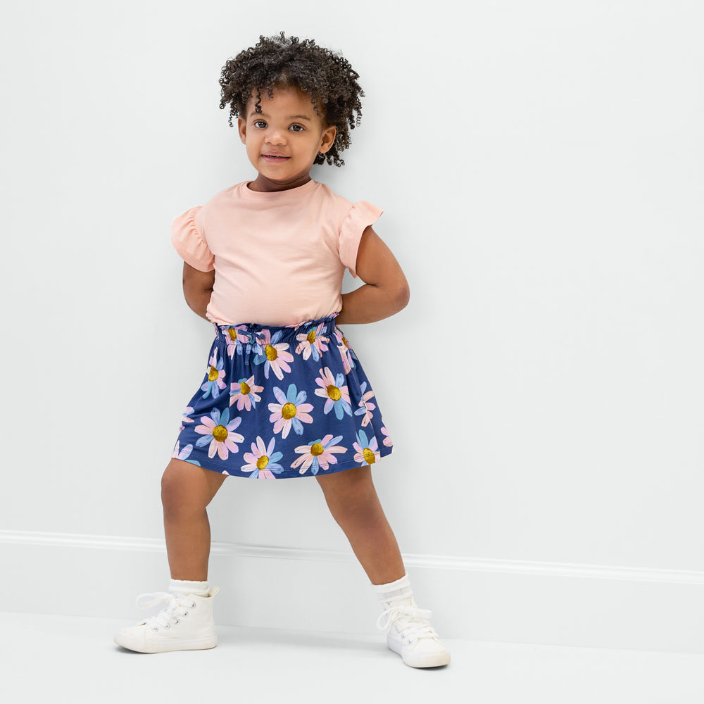 Standing child wearing the Peach Sorbet Ruffle Tee and the Daisy Blooms bamboo skort