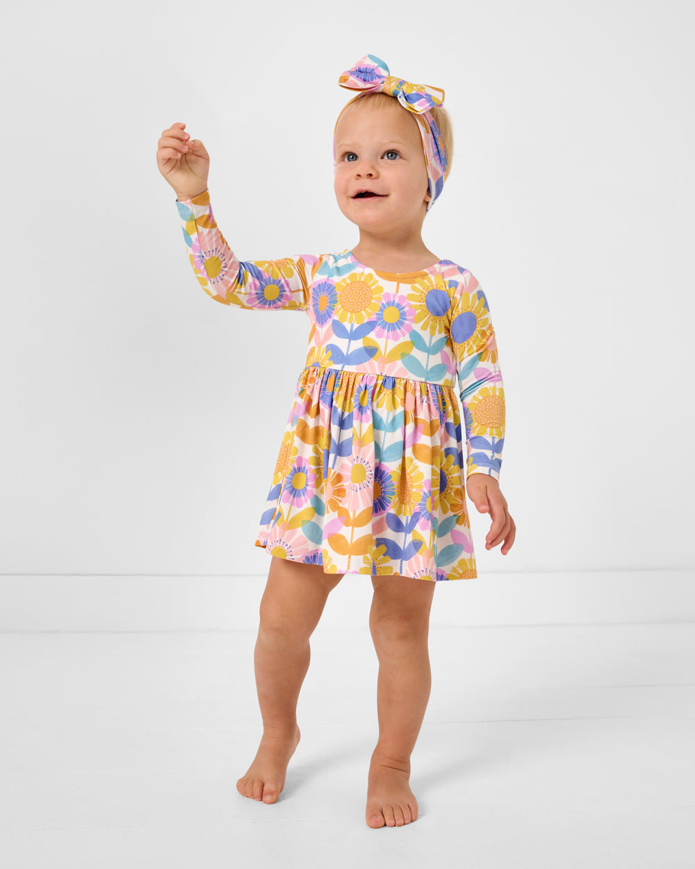 Standing girl wearing the Petal Power Bow Back Skater Dress with Bodysuit