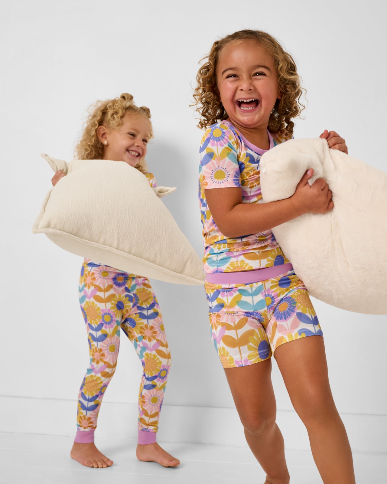 Two girls wearing matching matching Petal Power Two-Piece Pajama Set holding pillows