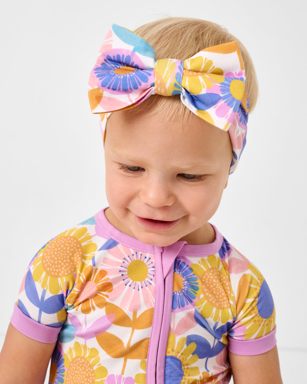 Baby wearing the Petal Power Luxe Bow Headband and matching shorty zippy