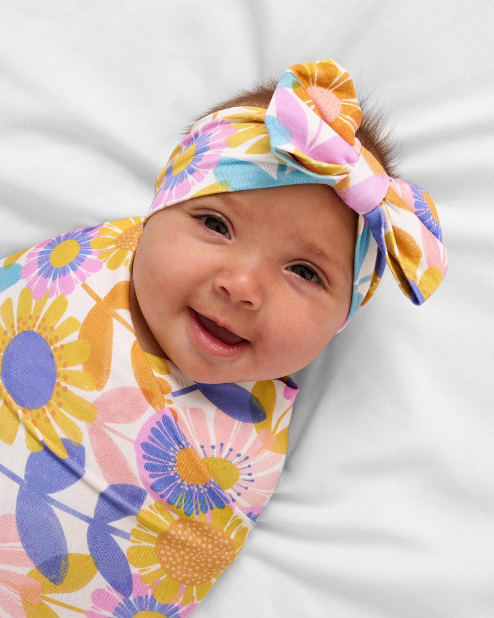 Close up of baby wearing the Petal Power Swaddle & Luxe Bow Headband Set