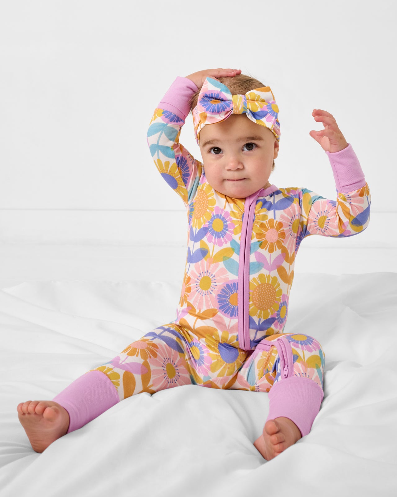 Baby on a white blanket wearing the Petal Power Zippy