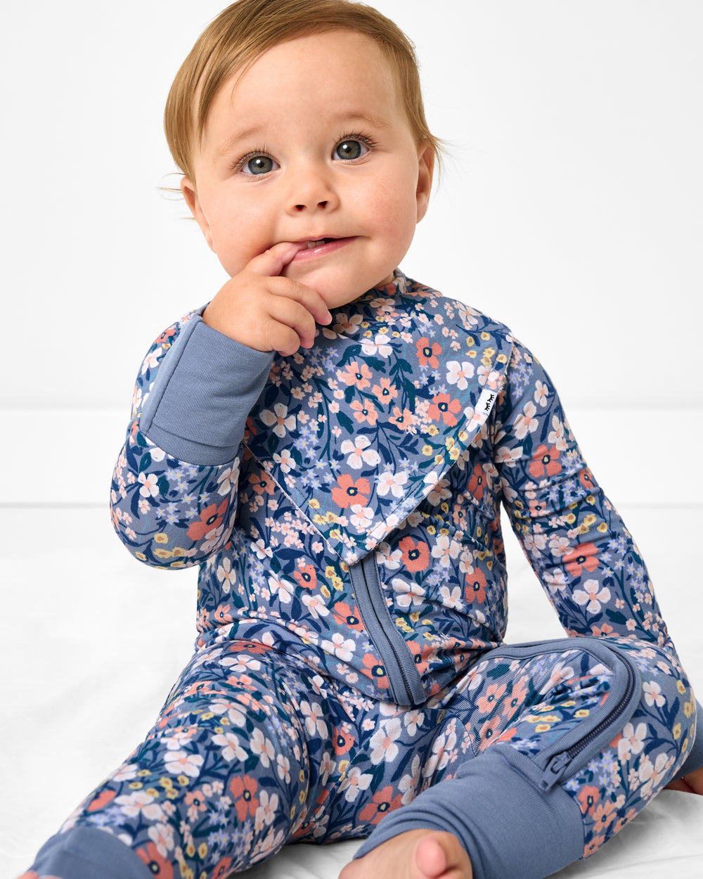 Baby wearing the Petite Petals Bandana Bib with a matching zipper pajamas