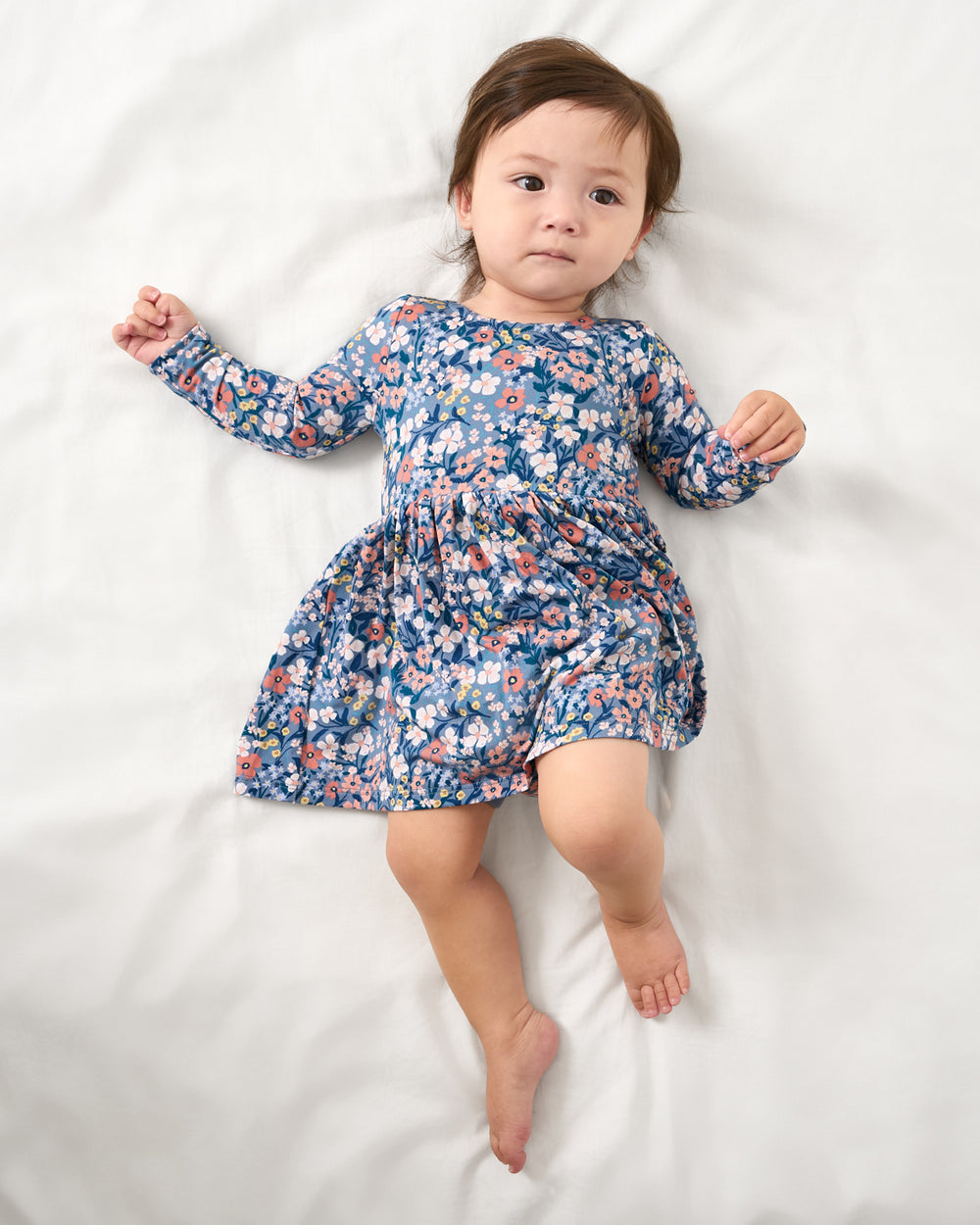Aerial view of baby wearing the Petite Petals Bow Back Skater Dress with Bodysuit