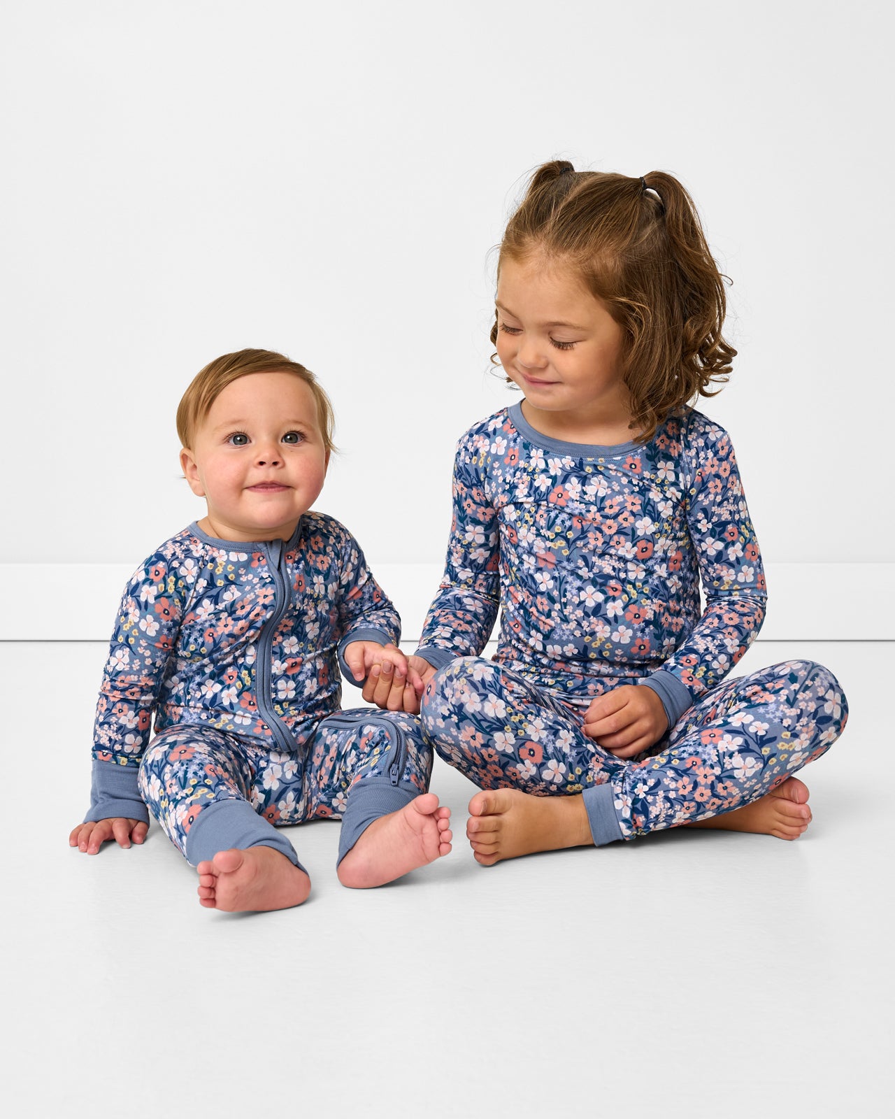 Two sitting children wearing matching Petite Petals floral pajamas