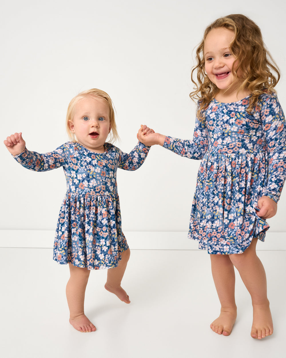 Two girls wearing matching Petite Petals Bow Back Skater Dresses