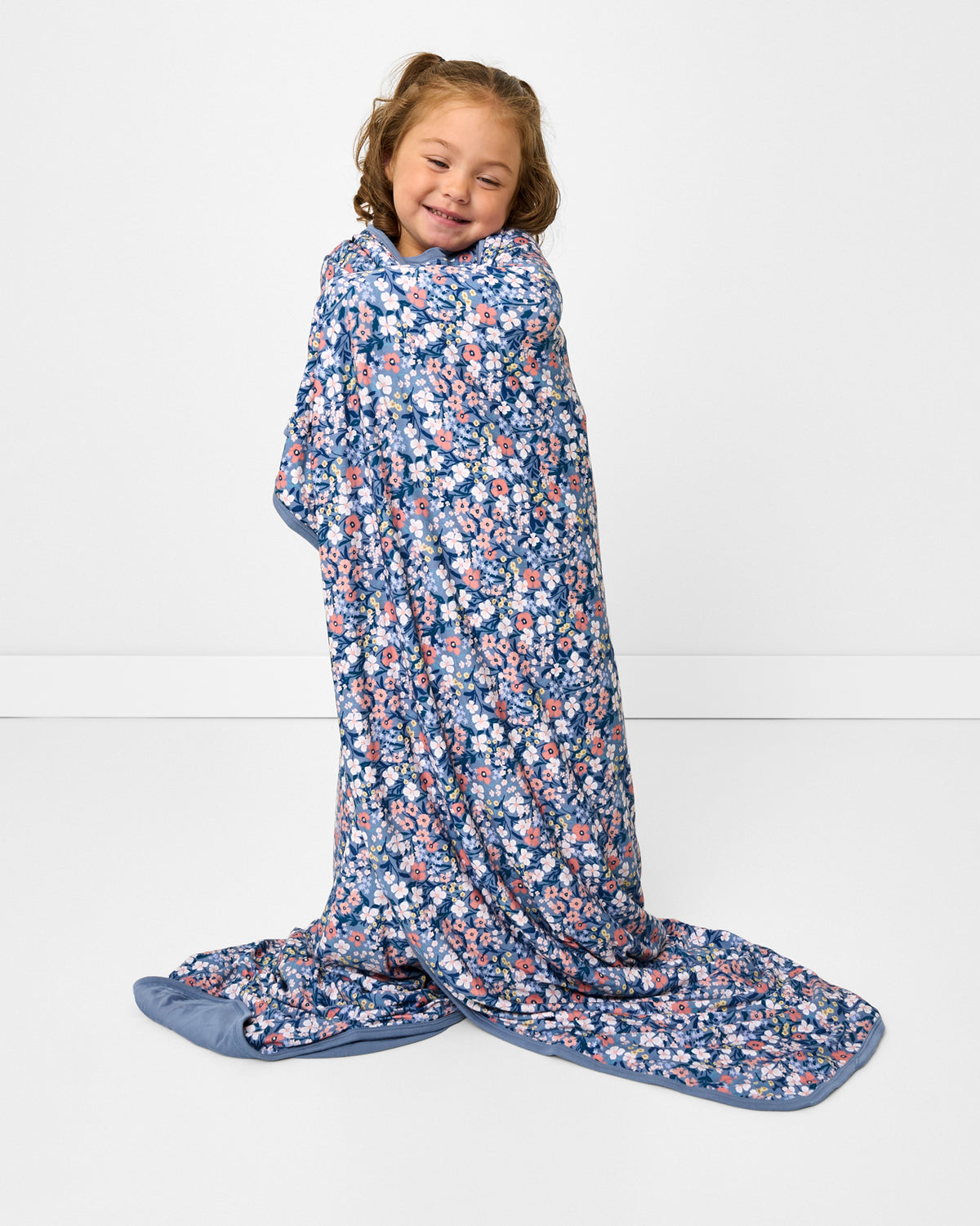 Standing girl wrapped in the Petite Petals Large Cloud Blanket®