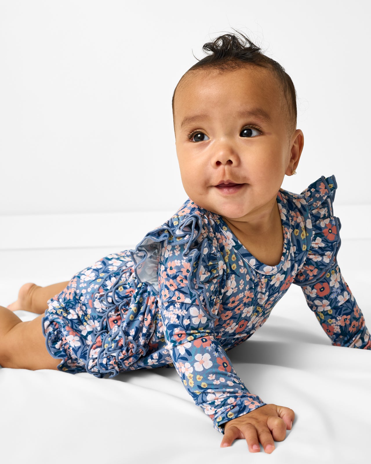 Baby wearing the Petite Petals Bubble Romper on a white background