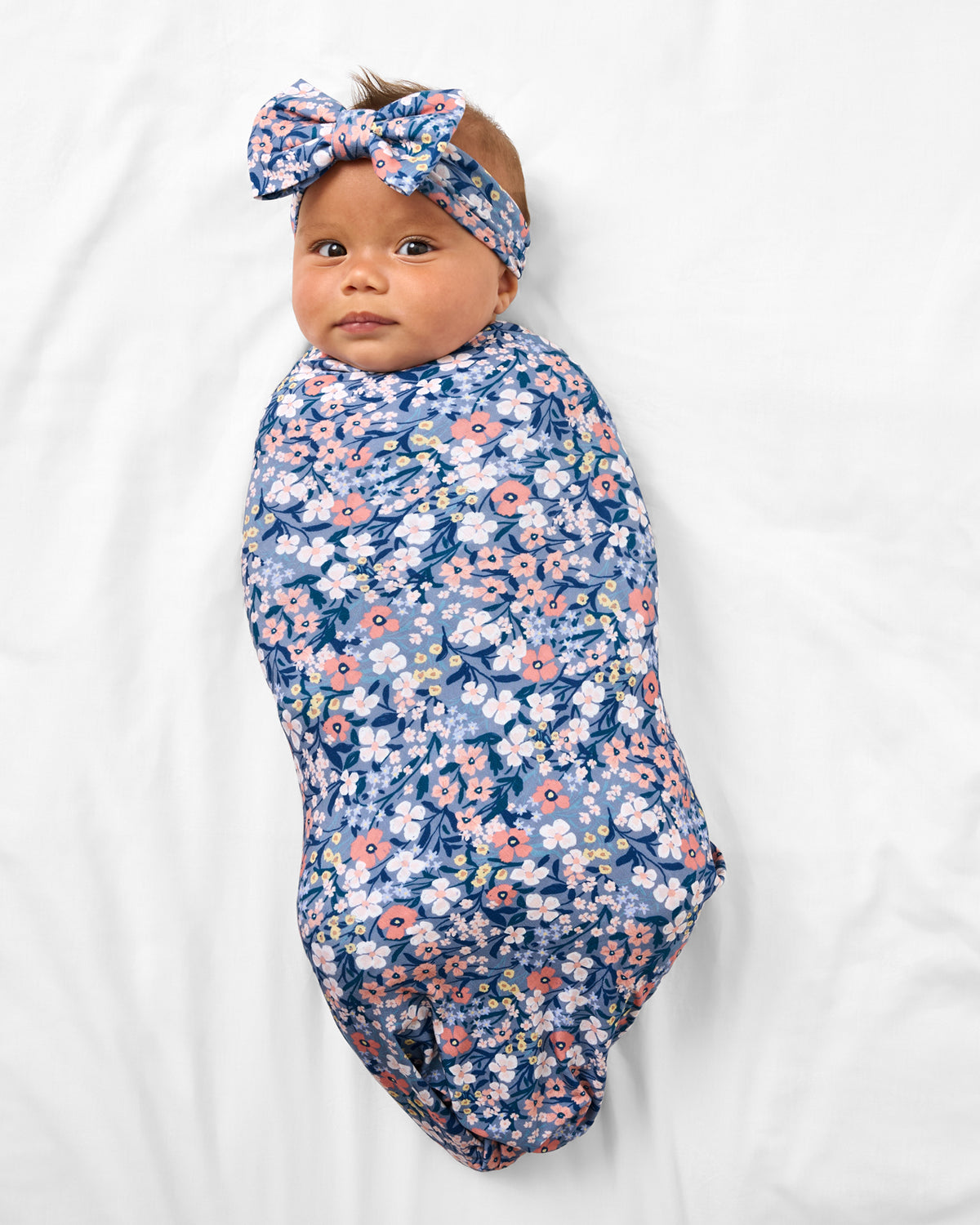 Aerial view of baby in the Petite Petals Swaddle & Luxe Bow Headband Set