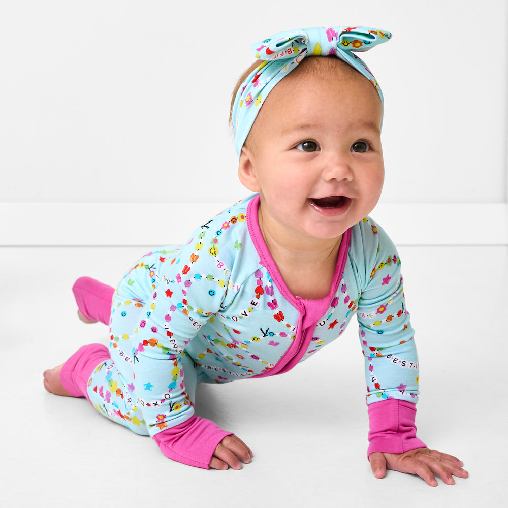 Crawling child wearing the Friends Forever Luxe Bow Headband and matching friendship bracelet themed pjs