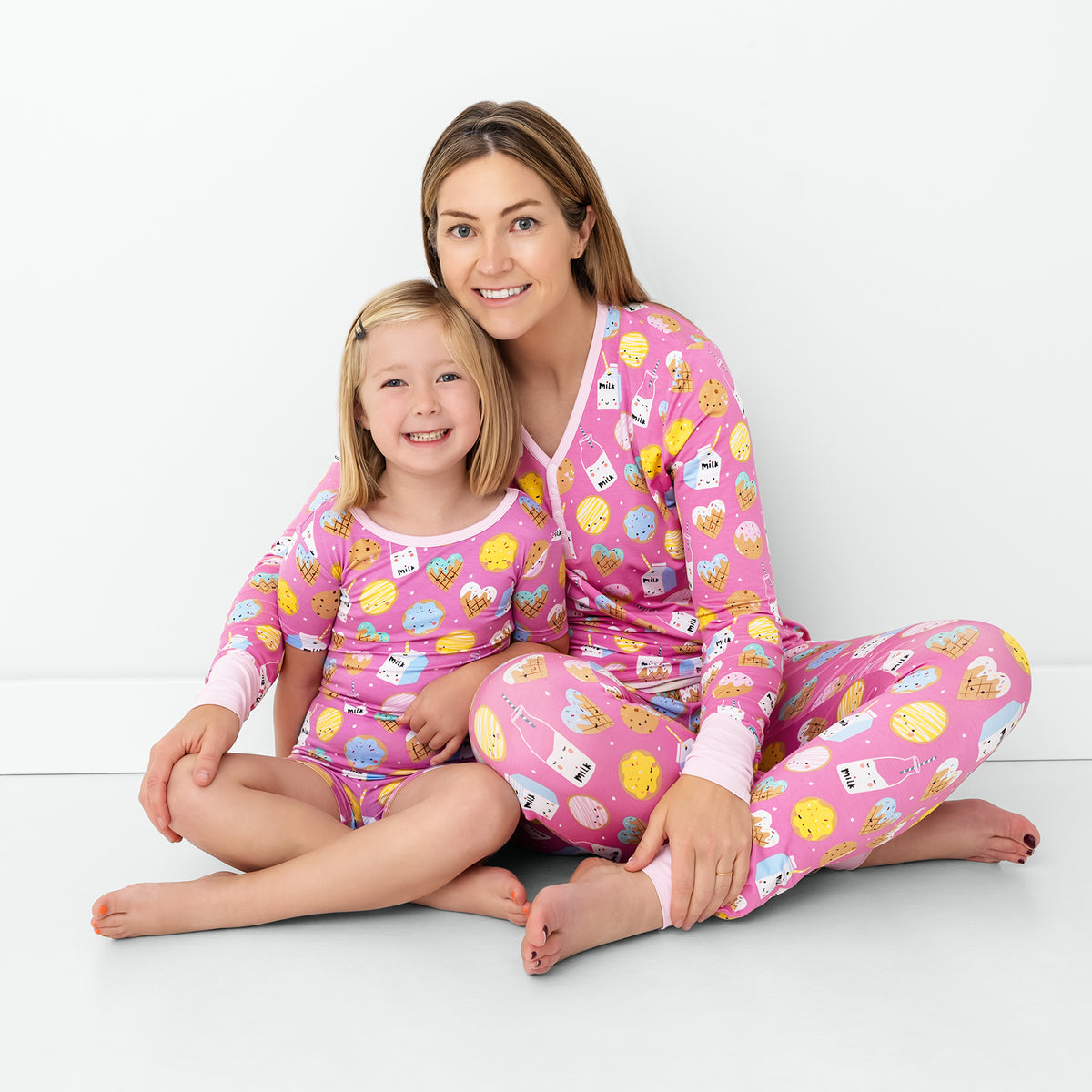 Sitting mother and daughter wearing matching Pink Cookies & Milk pajamas