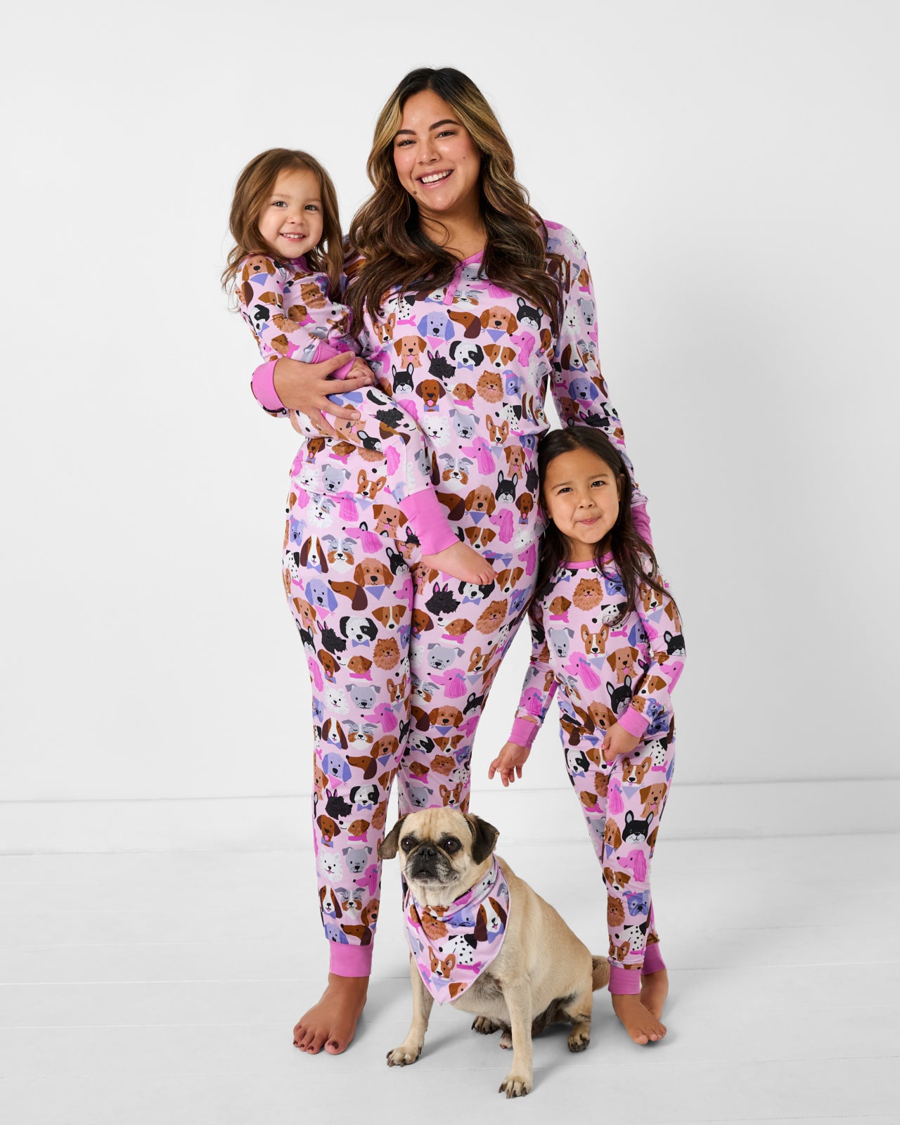 Family of three and a dog wearing matching Pink Puppy Parade pajamas