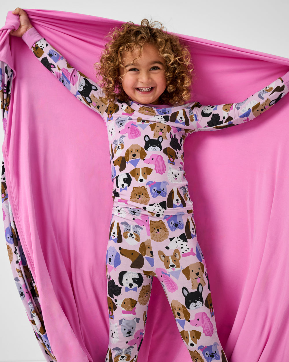 Child holding up the Pink Puppy Parade Large Cloud Blanket® showing the solid pink side