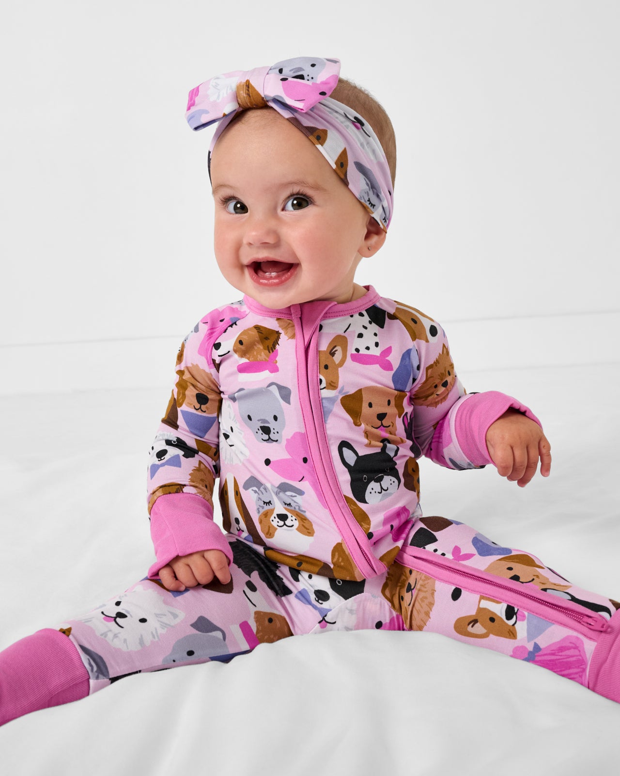Sitting baby wearing the Pink Puppy Parade Zippy