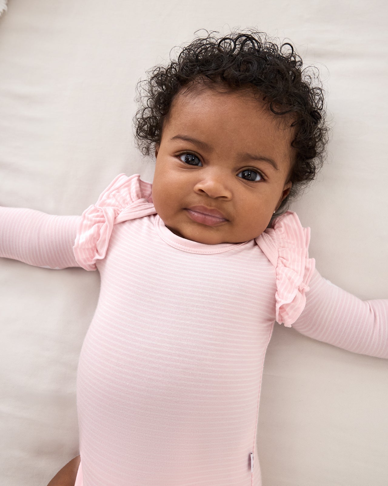 Close up of newborn wearing the Prima Pink Stripe Flutter Bodysuit on a white background