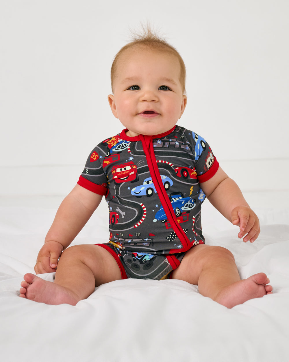 Sitting baby wearing the Disney & Pixar Piston Cup Shorty Zippy