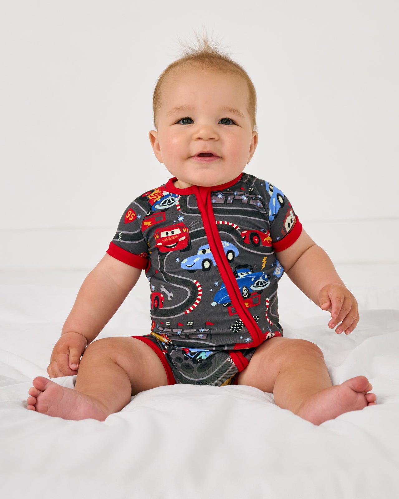 Sitting baby wearing the Disney & Pixar Piston Cup Shorty Zippy