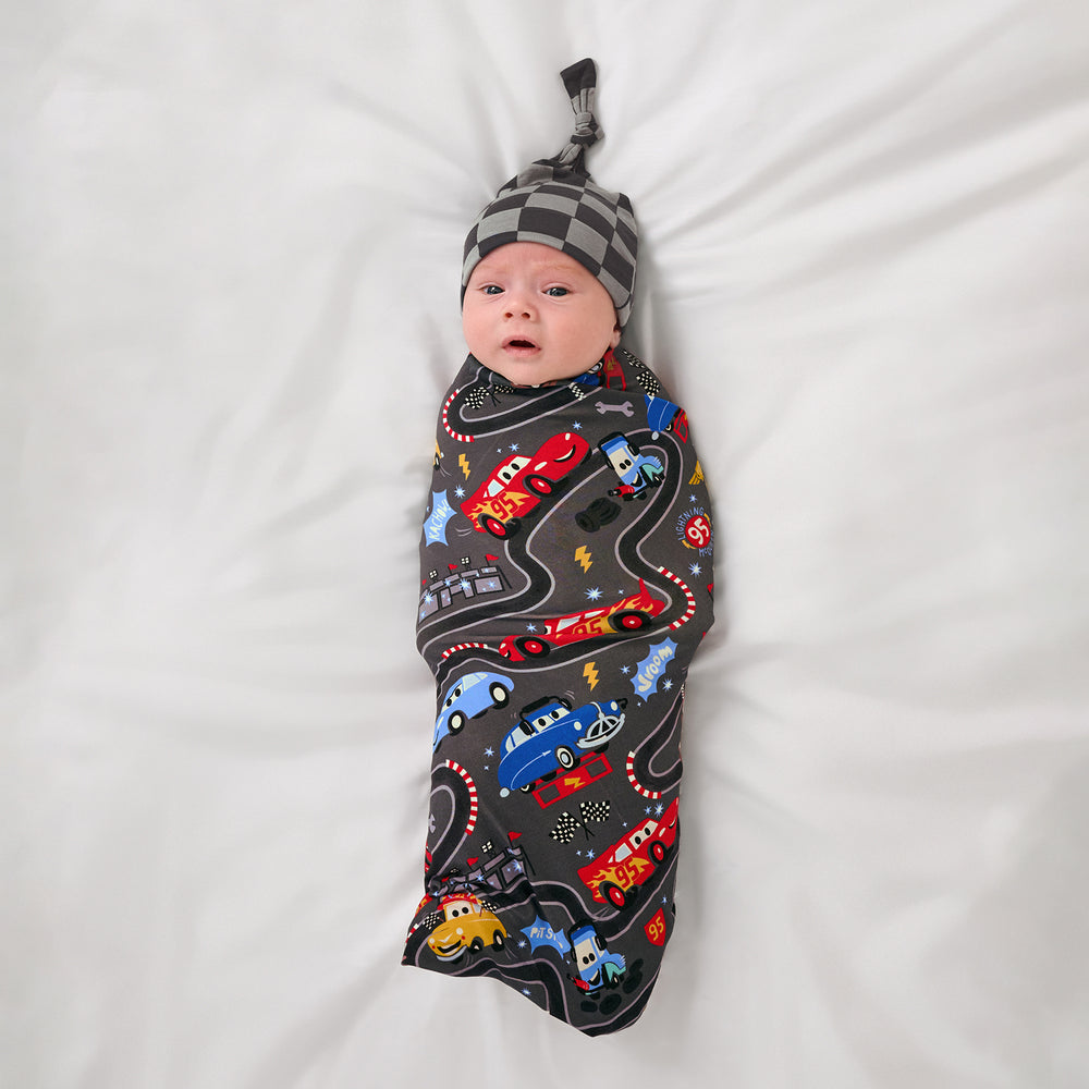 Aerial view of baby wearing the Disney & Pixar Piston Cup Swaddle & Hat Set