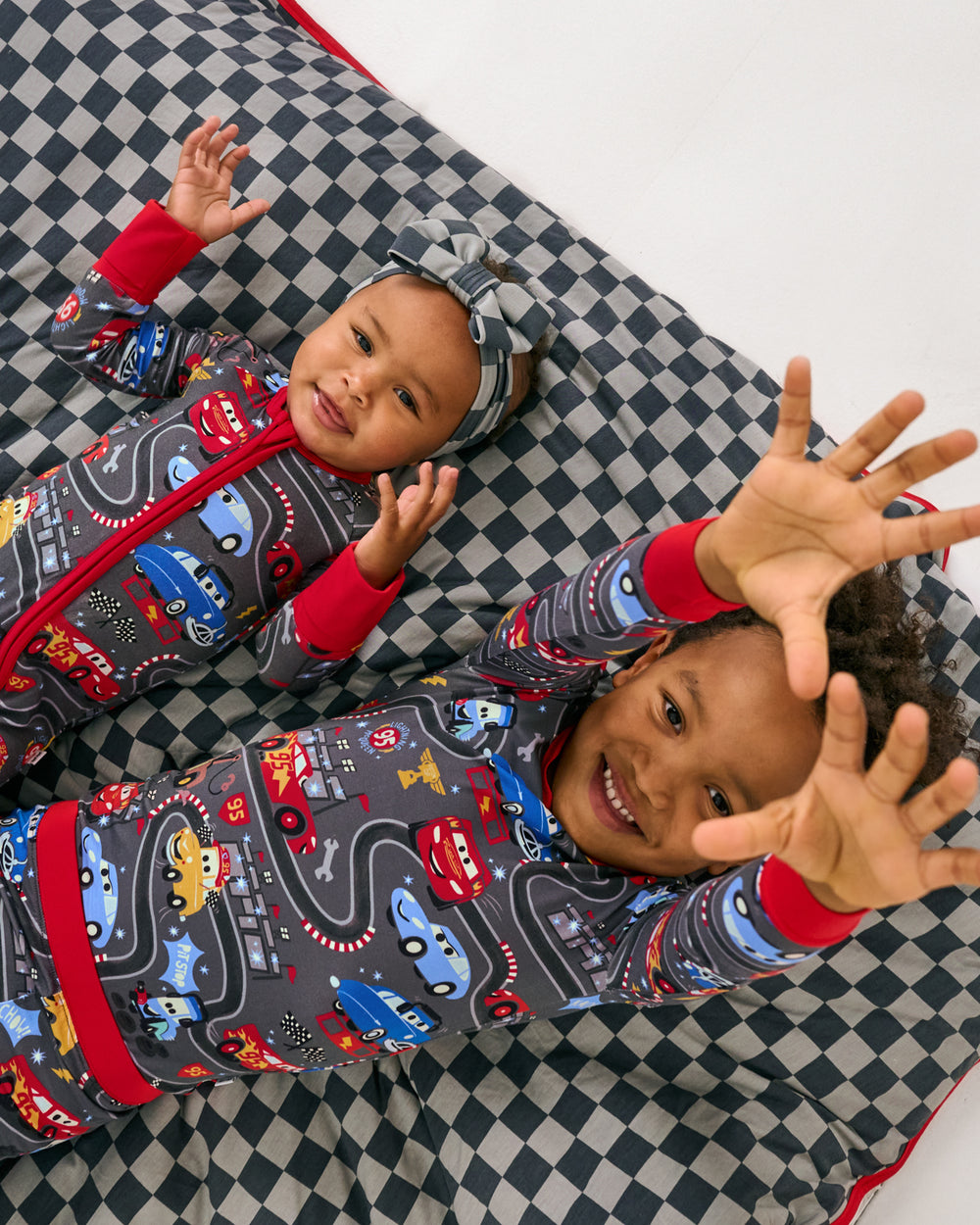 Two children laying on the Disney & Pixar Piston Cup Large Cloud Blanket®