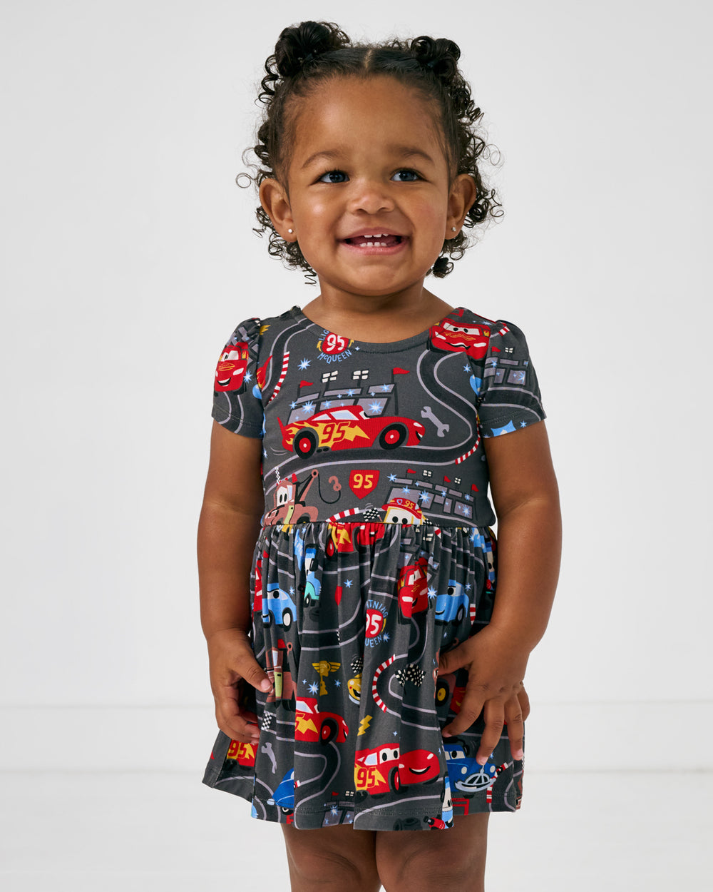 Close up of girl wearing the Disney & Pixar Piston Cup Bow Back Skater Dress with Bodysuit