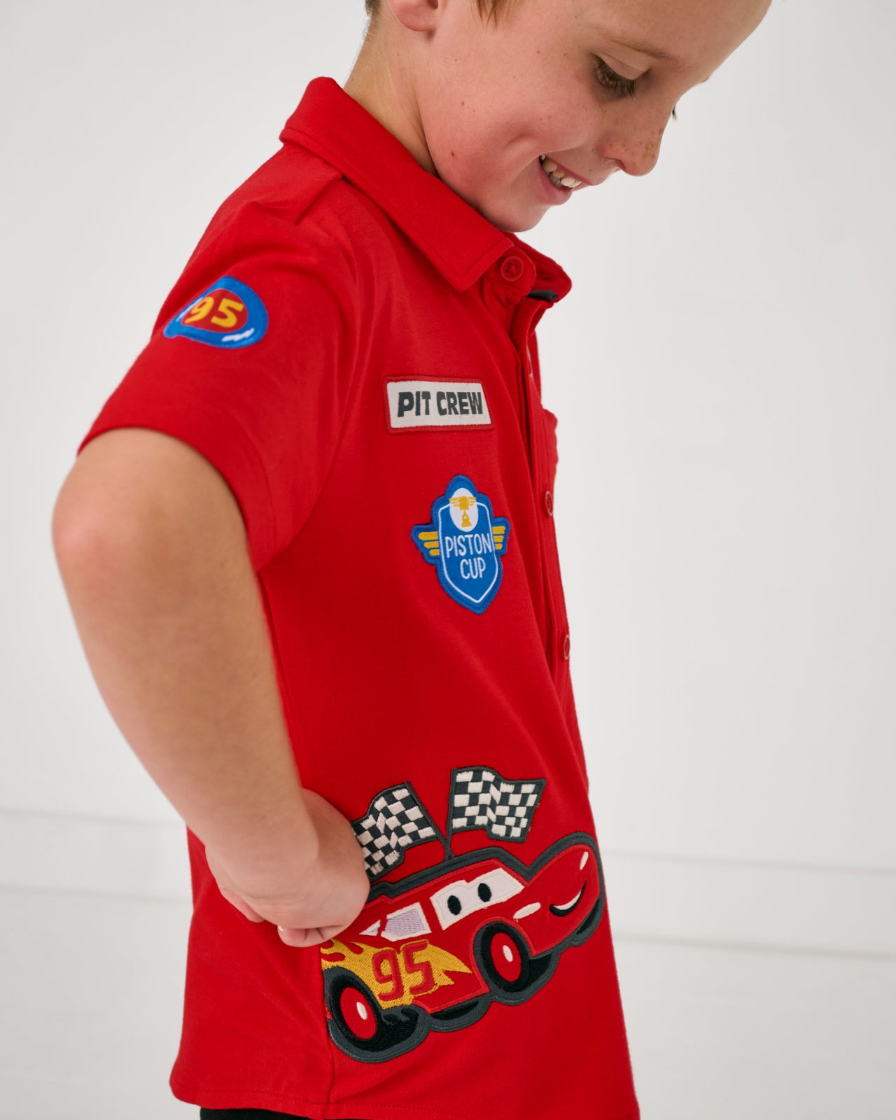 Close up side view of boy wearing the Disney & Pixar Piston Cup Button Down Polo