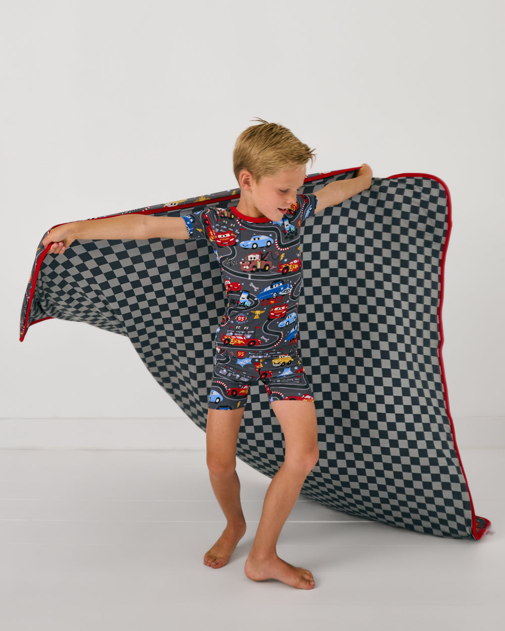 Boy in motion holding up the Disney & Pixar Piston Cup Large Cloud Blanket®