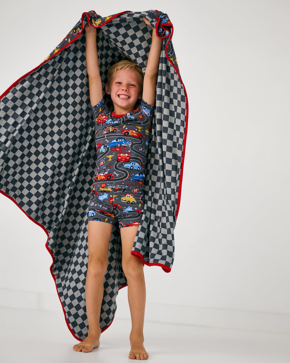 Boy holding up the Disney & Pixar Piston Cup Large Cloud Blanket®