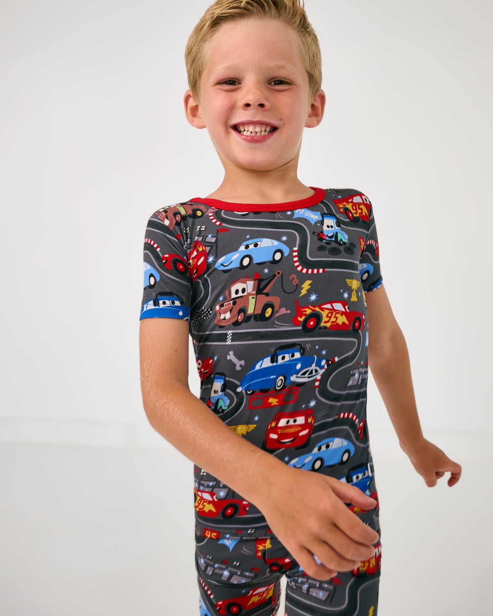 Boy in motion wearing the Disney & Pixar Piston Cup Two-Piece Short Sleeve & Shorts Pajama Set