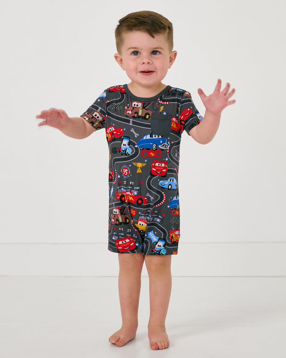 Posing toddler wearing the Disney & Pixar Piston Cup Pocket Shorty Romper
