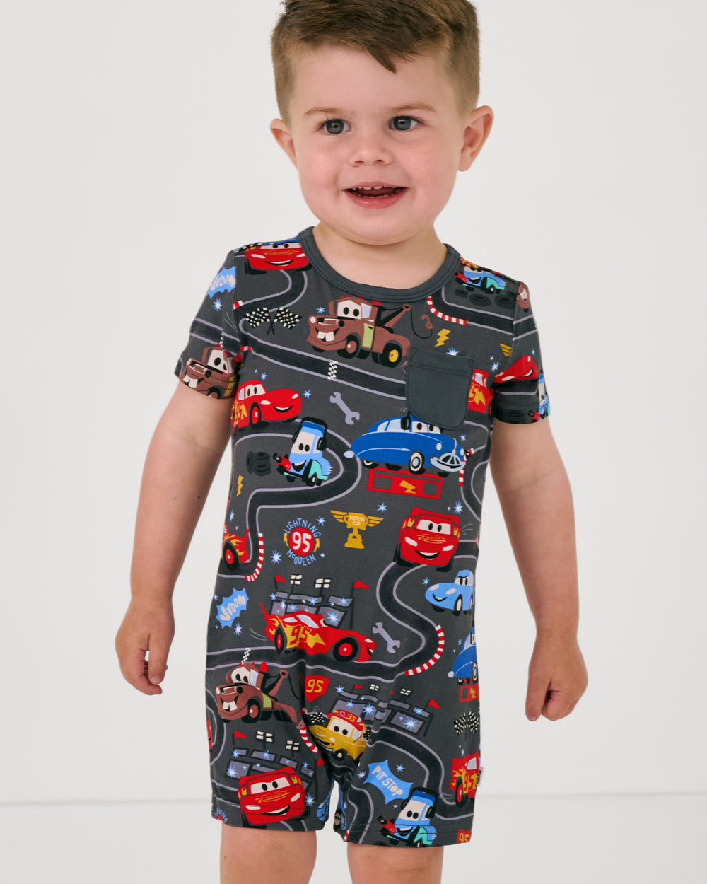 Standing toddler wearing the Disney & Pixar Piston Cup Pocket Shorty Romper