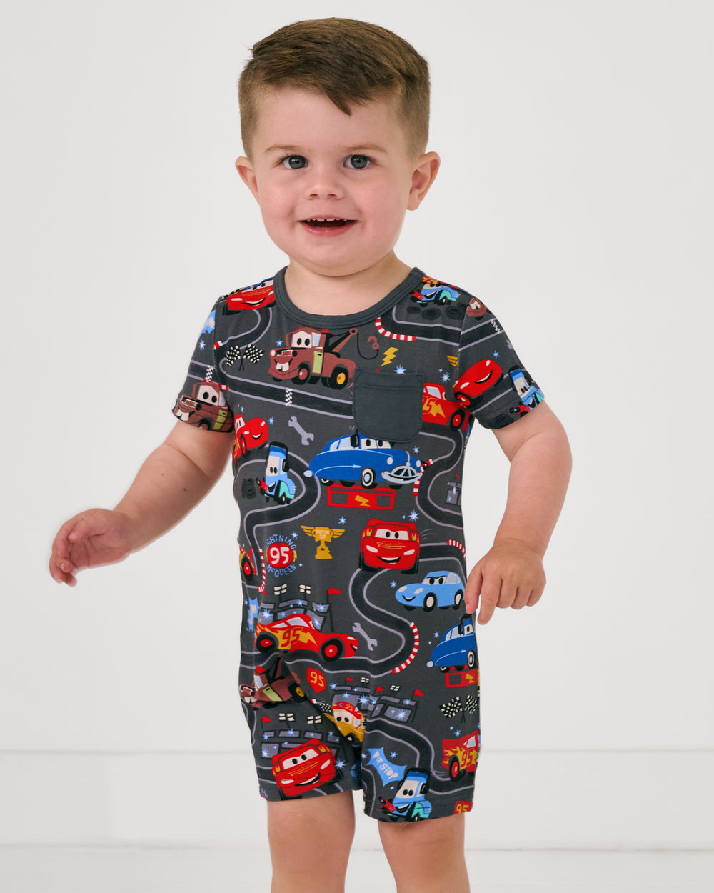 Close up of toddler wearing the Disney & Pixar Piston Cup Pocket Shorty Romper