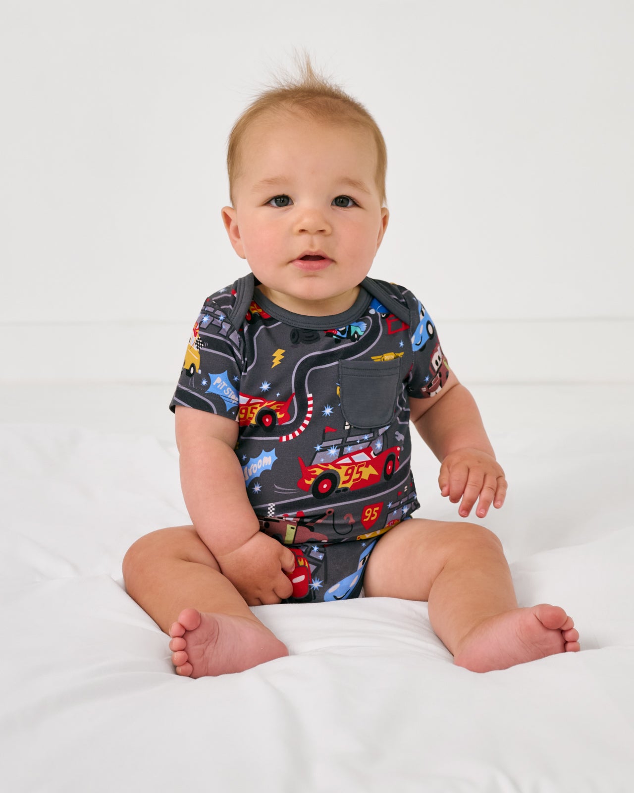 Sitting baby wearing the Disney & Pixar Piston Cup Pocket Bodysuit