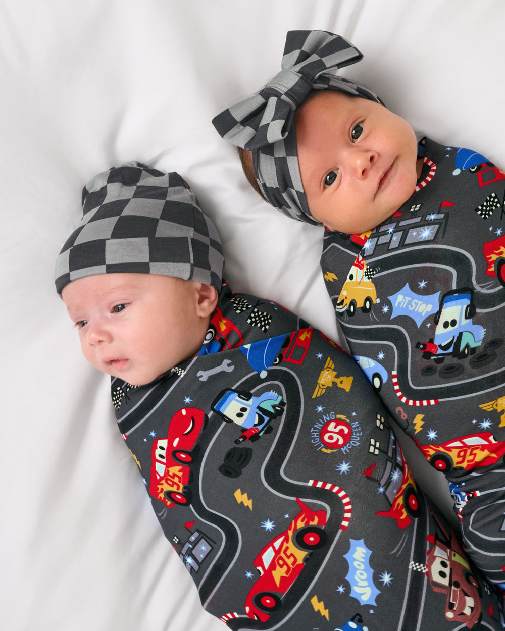 Two babies wearing Disney & Pixar Piston Cup Swaddle sets