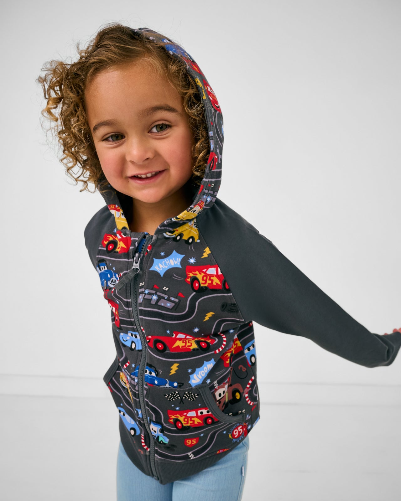 Girl wearing the Disney & Pixar Piston Cup Zip Hoodie with the hood on