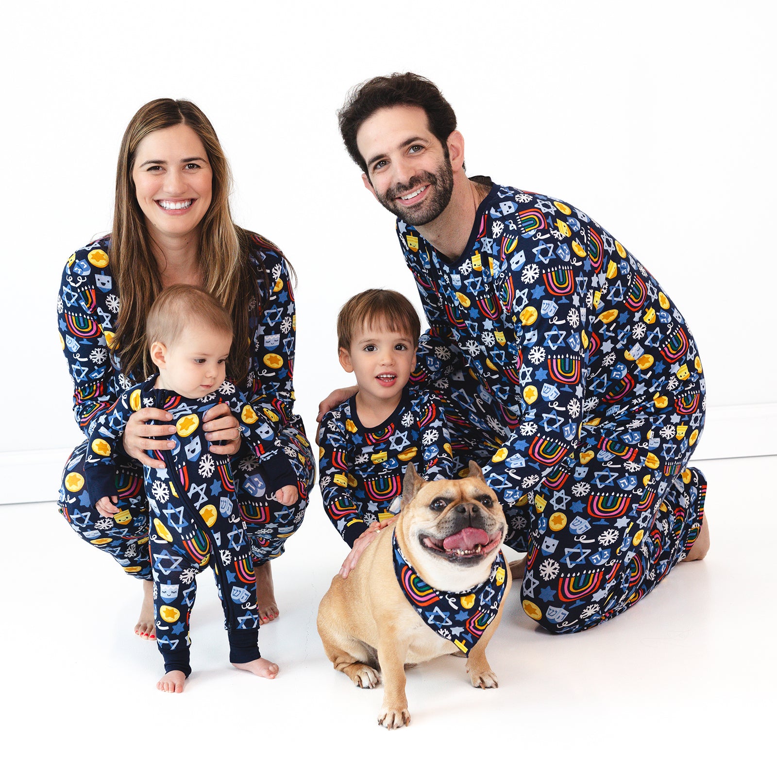 Family of four and a dog wearing matching Playful Dreidels pajamas