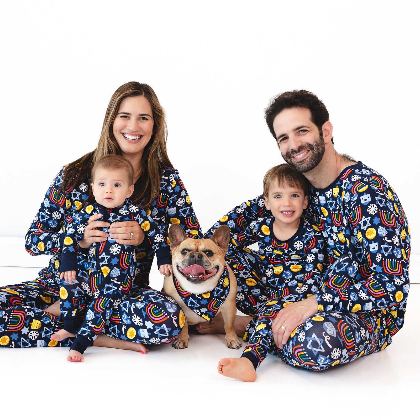 Family of four and a dog wearing matching Playful Dreidels pajamas