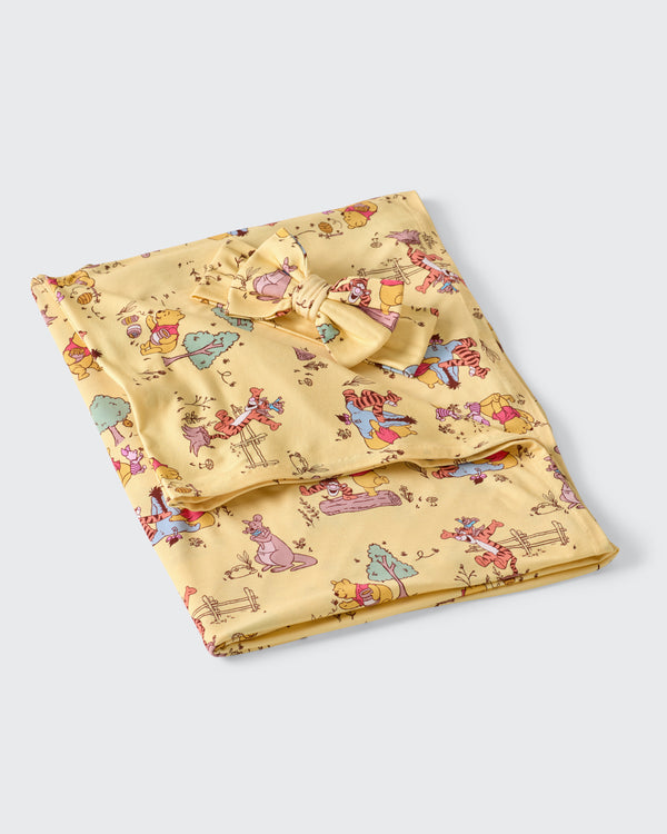 Flat lay of the Disney Playtime With Pooh Swaddle & Luxe Bow Headband Set