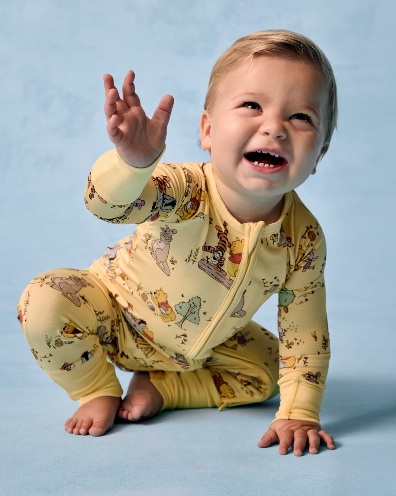 Crawling baby wearing the Disney Playtime With Pooh Zippy on a blue background