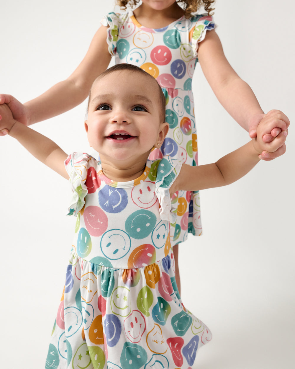 Two children holding hands in matching Positive Vibes Flutter Twirl Dresses