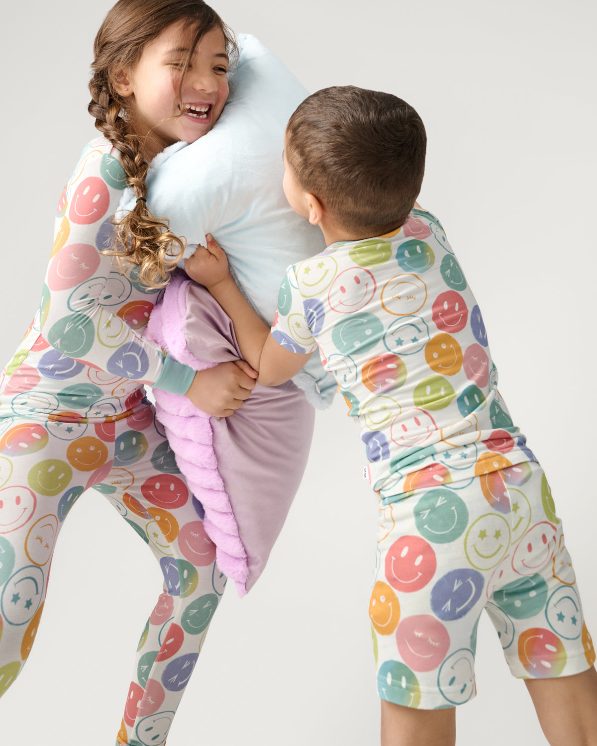 Two children having a pillow fight wearing matching Positive Vibes Two-Piece Pajama Sets