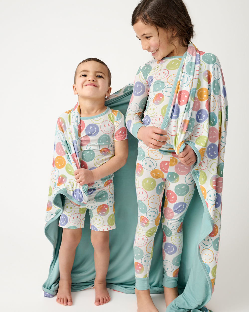 Two children wrapped in the Positive Vibes Large Cloud Blanket®