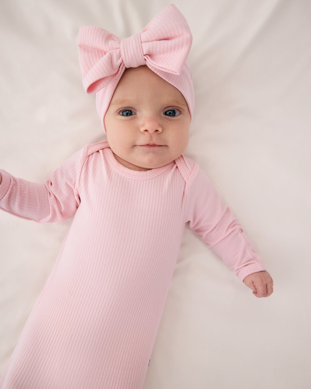 Baby wearing the Prima Pink Ribbed Infant Gown with a matching pink luxe bow headband