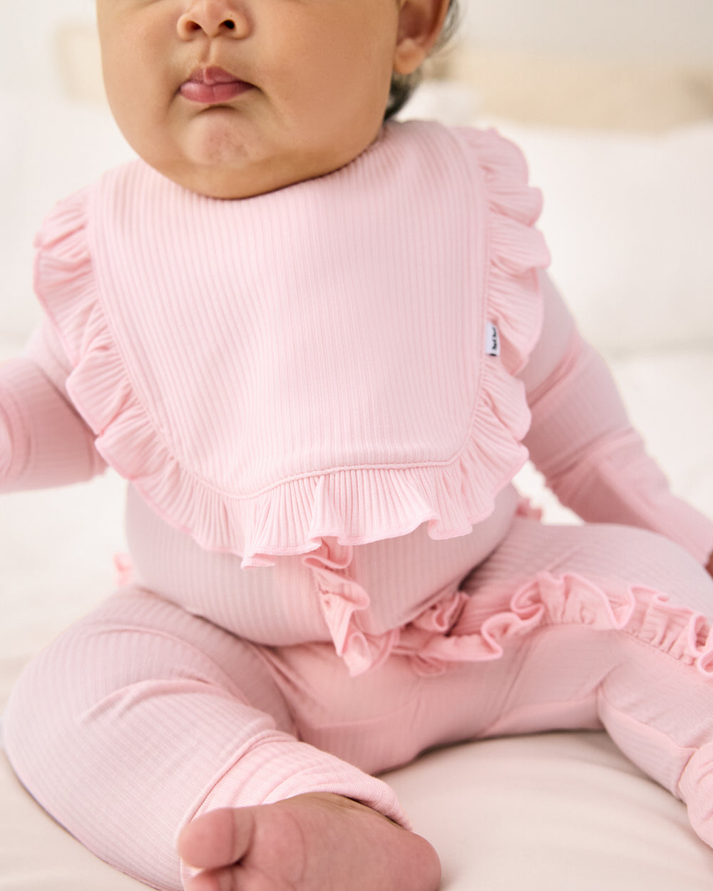 Close up of newborn girl wearing the Prima Pink Ribbed Ruffle Bib
