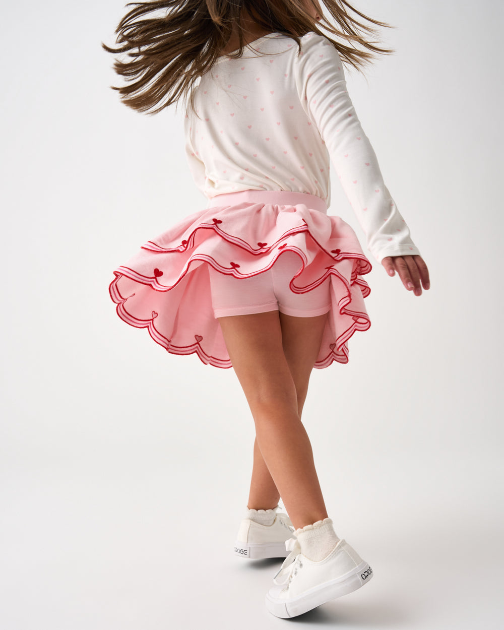 Child in motion wearing the Prima Pink Scalloped Skort with built in shorts