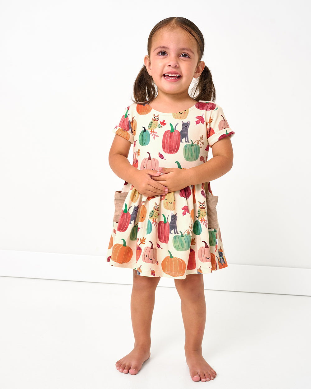 Standing toddler wearing the Pumpkin Pals Patch Pocket Dress with Bloomer
