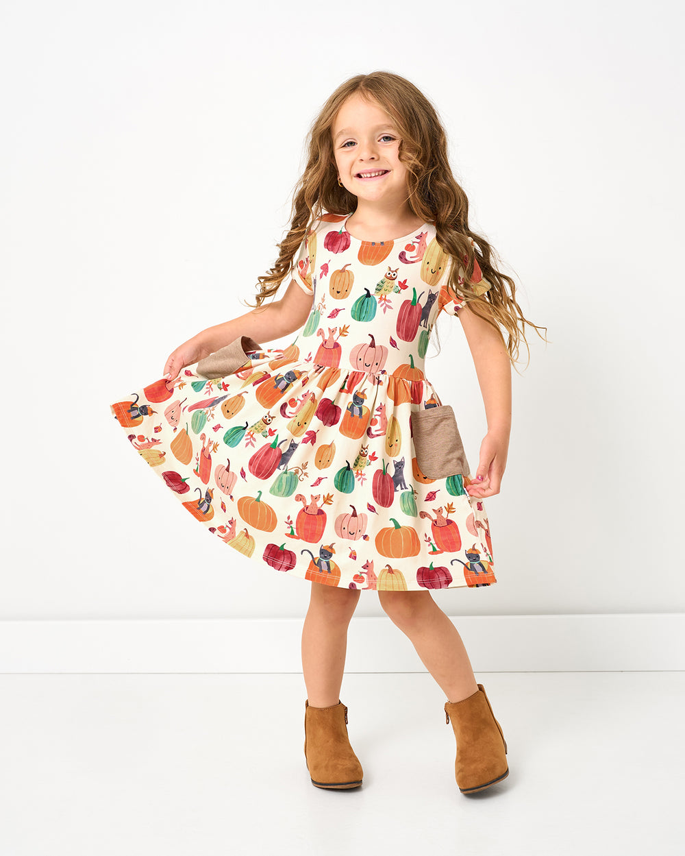 Girl wearing the Pumpkin Pals Patch Pocket Dress with suede booties