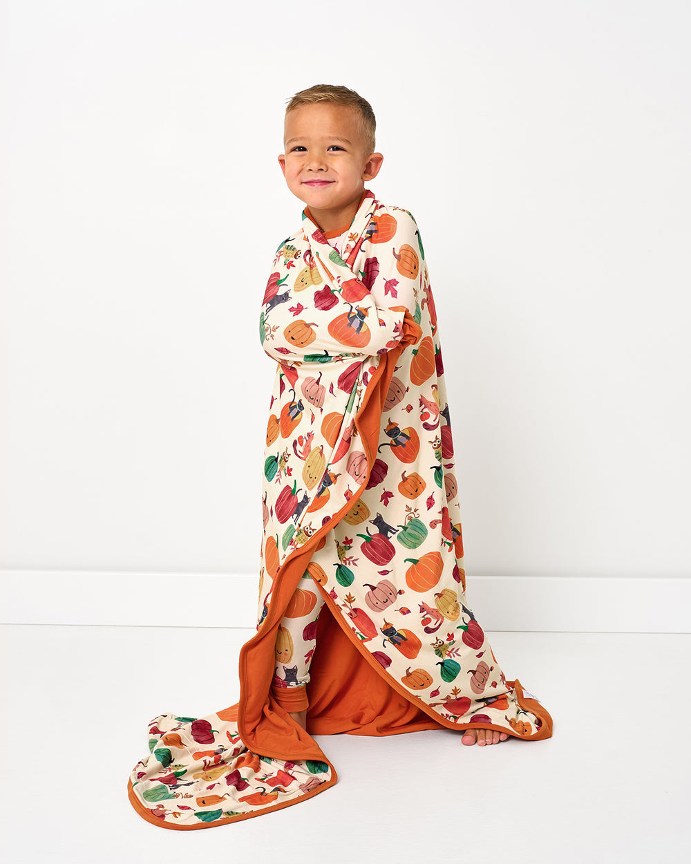 Standing boy wrapped in the Pumpkin Pals Large Cloud Blanket®