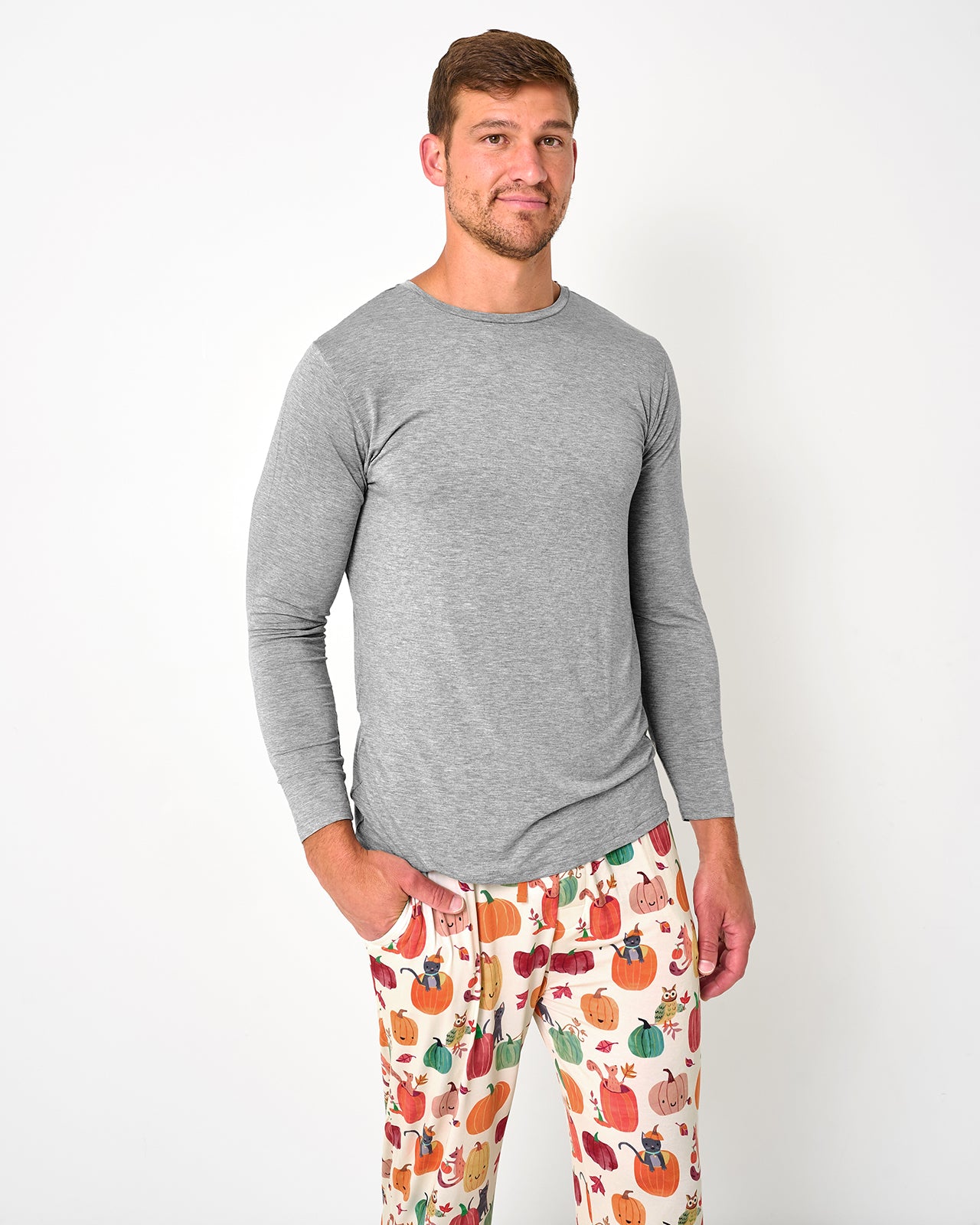 Man wearing the Pumpkin Pals Men's Pajama Pants with a heather gray long sleeve pajama top
