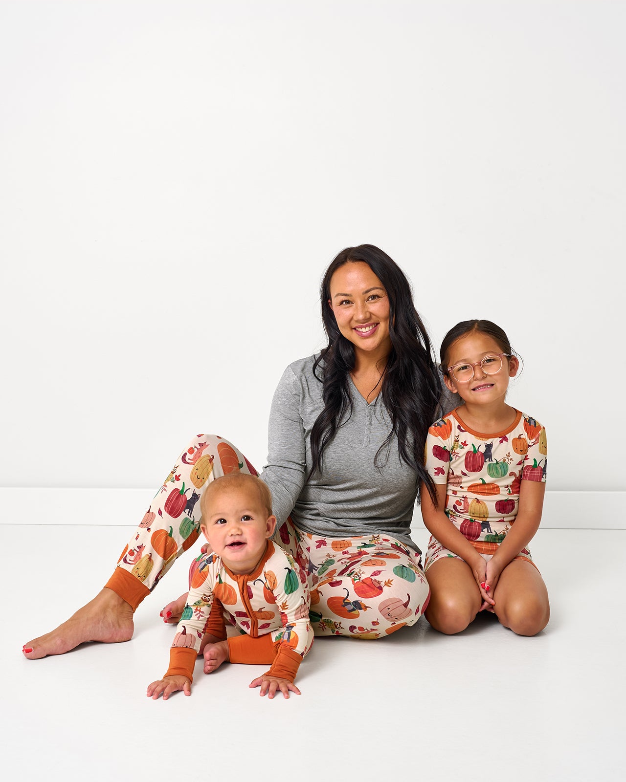 Mother and two children wearing matching Pumpkin Pals pajamas for fall